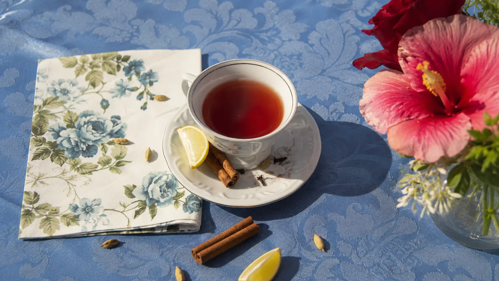 Tea with lemon and hibiscus flowers on a blue tablecloth
